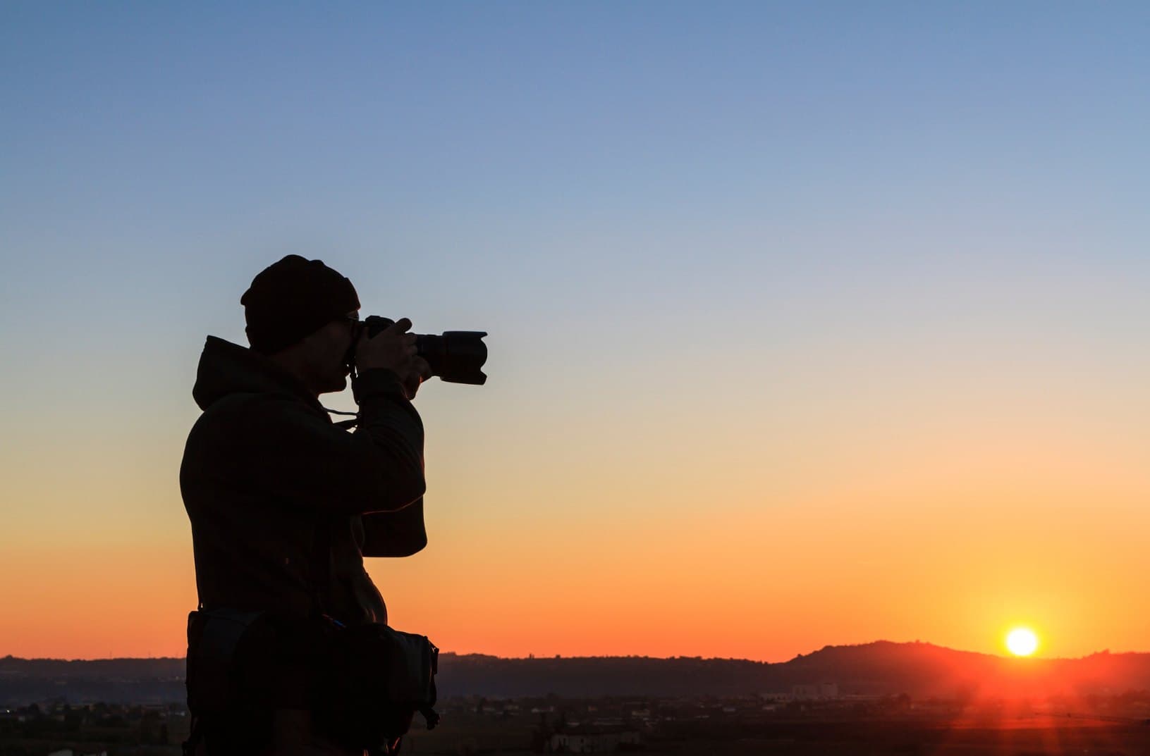 Photographer silhouetted against a sunset horizon