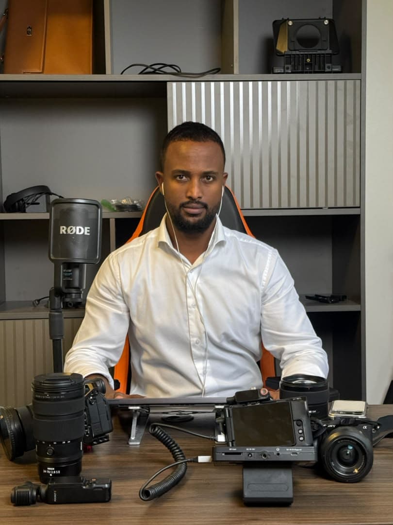 Kamil Ahmed at his desk with cameras, lenses and a RØDE microphone