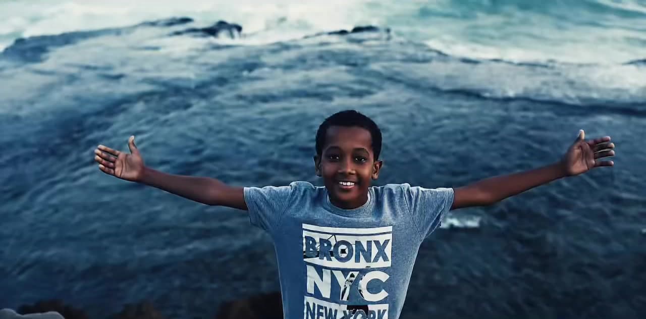 A boy with his arms wide open in front of the waves in Mogadishu